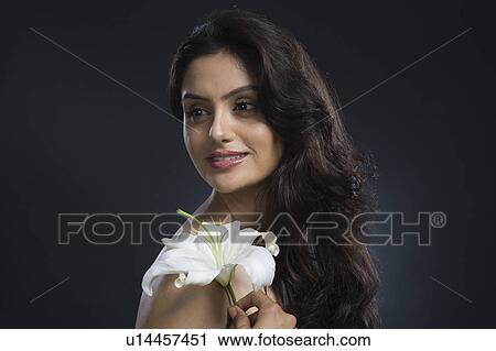 Stock Image - Woman holding a Tiger Lily flower and day dreaming. Fotosearch