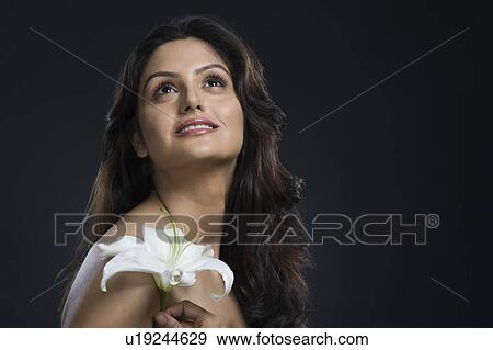 Stock Photo - Woman holding a Tiger Lily flower and day dreaming. Fotosearch