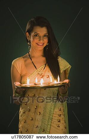 Stock Photo - Woman holding a traditional Diwali thali and smiling. Fotosearch