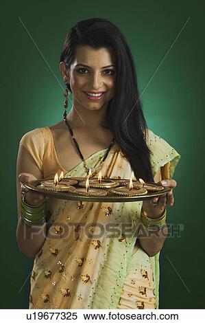Stock Photography - Woman holding a traditional Diwali thali and smiling. Fotosearch