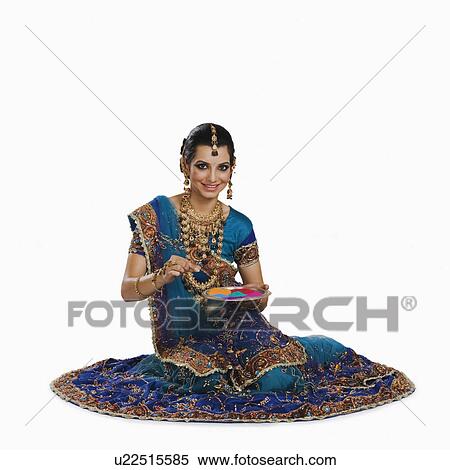 Stock Photography - Woman holding a tray of powder paints to make rangoli at Diwali festival. Fotosearch