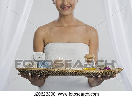 Stock Image - Woman holding a tray of spa products and smiling. Fotosearch