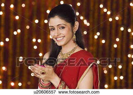 Stock Photo - Woman holding an oil lamp and smiling. Fotosearch