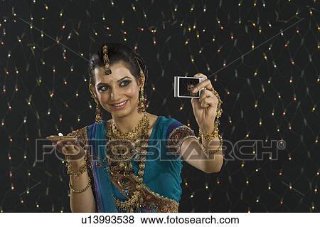 Woman holding an oil lamp and taking a picture of herself with a digital camera View Large Photo Image Stock Photo - Woman holding an oil lamp and taking a picture of herself with a digital camera. Fotosearch