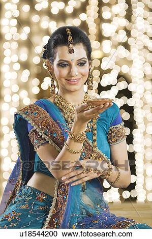 Stock Image - Woman holding an oil lamp at Diwali festival. Fotosearch