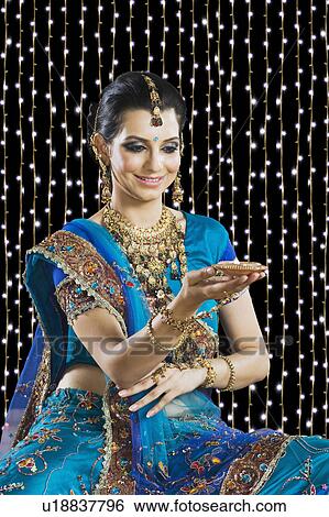 Stock Photograph - Woman holding an oil lamp at Diwali festival. Fotosearch