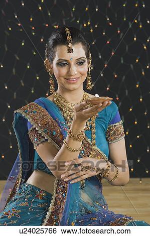 Woman holding an oil lamp at Diwali festival View Large Photo Image Stock Photograph - Woman holding an oil lamp at Diwali festival. Fotosearch