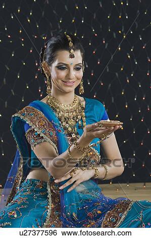 Woman holding an oil lamp at Diwali festival View Large Photo Image Stock Photograph - Woman holding an oil lamp at Diwali festival. Fotosearch