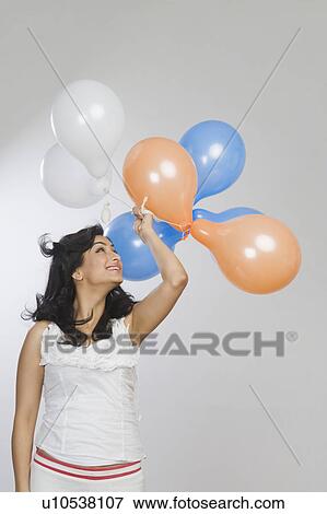 Stock Photo - Woman holding balloons and smiling. Fotosearch