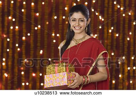 Stock Image - Woman holding Diwali gift and smiling. Fotosearch