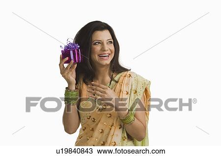 Stock Image - Woman holding Diwali gift and smiling. Fotosearch