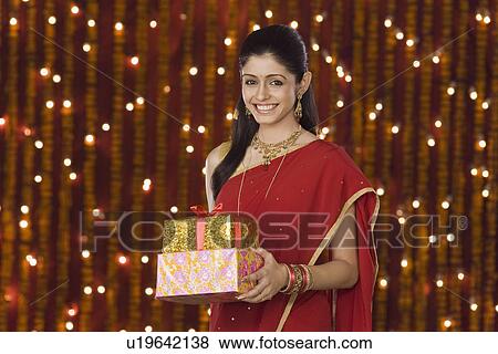 Woman holding Diwali gift and smiling View Large Photo Image Stock Photo - Woman holding Diwali gift and smiling. Fotosearch