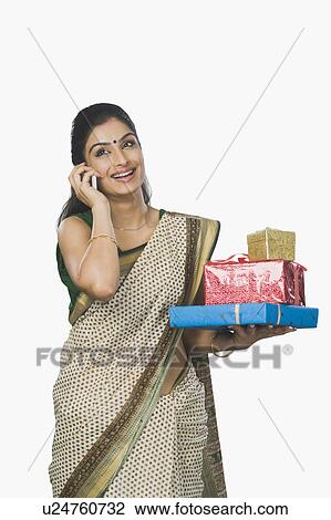 Woman holding gifts and talking on a mobile phone View Large Photo Image Stock Image - Woman holding gifts and talking on a mobile phone. Fotosearch