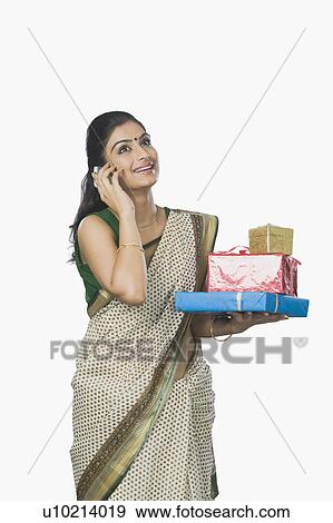 Stock Photo - Woman holding gifts and talking on a mobile phone. Fotosearch