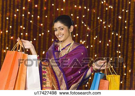 Stock Photo - Woman holding shopping bags and smiling. Fotosearch