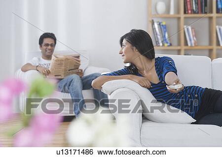 Woman holding TV remote control and talking to her husband View Large Photo Image Stock Photograph - Woman holding TV remote control and talking to her husband. Fotosearch