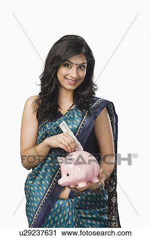 Stock Image - Woman inserting money into a piggybank. Fotosearch