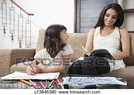 Stock Image - Woman looking at her daughter drawing. Fotosearch