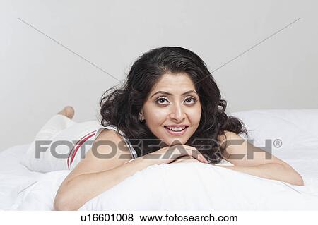 Stock Photo - Woman lying on the bed and smiling. Fotosearch