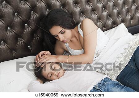 Woman making her daughter sleep View Large Photo Image Stock Photo - Woman making her daughter sleep. Fotosearch