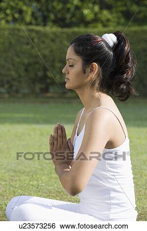 Stock Photograph - Woman meditating in a park. Fotosearch