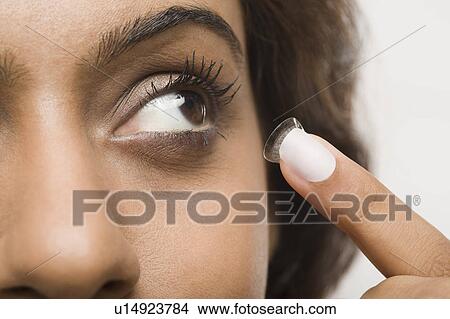 Picture - Woman putting on contact lens. Fotosearch