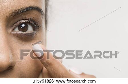 Stock Photograph - Woman putting on contact lens. Fotosearch