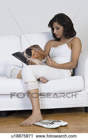 Woman reading a magazine on a couch View Large Photo Image Stock Image - Woman reading a magazine on a couch. Fotosearch