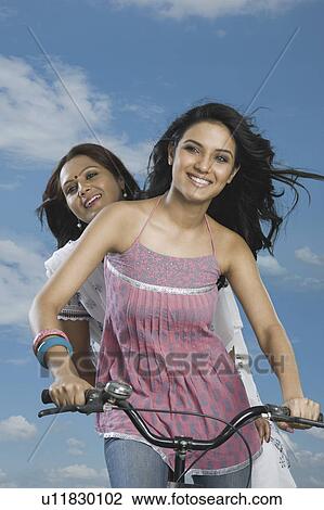 Woman riding a bicycle with her mother sitting behind her View Large Photo Image Stock Image - Woman riding a bicycle with her mother sitting behind her. Fotosearch