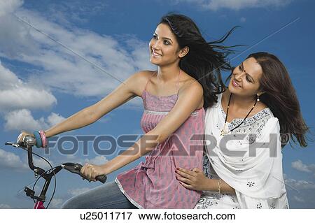 Woman riding a bicycle with her mother sitting behind her View Large Photo Image Stock Photo - Woman riding a bicycle with her mother sitting behind her. Fotosearch