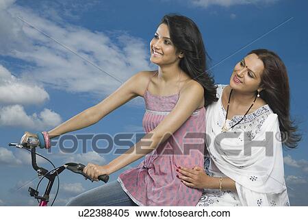 Woman riding a bicycle with her mother sitting behind her View Large Photo Image Stock Photography - Woman riding a bicycle with her mother sitting behind her. Fotosearch