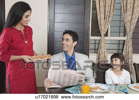 Stock Photo - Woman serving breakfast to her family. Fotosearch