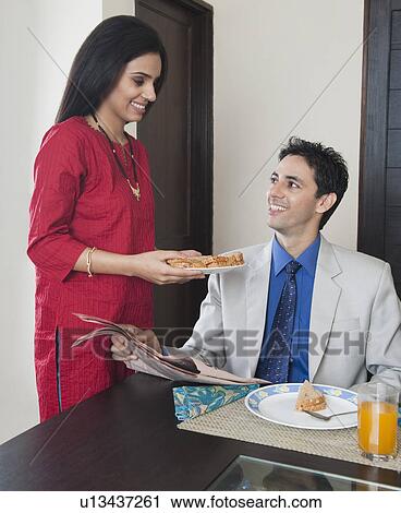 Stock Image - Woman serving breakfast to her husband. Fotosearch
