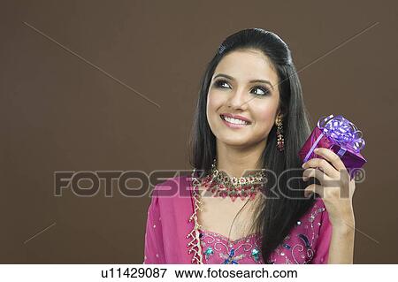 Stock Photo - Woman shaking her gift and smiling. Fotosearch