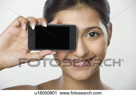 Stock Image - Woman showing a mobile phone and smiling. Fotosearch