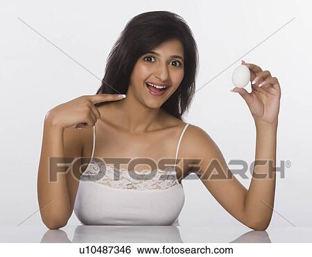 Stock Photograph - Woman showing an egg and smiling. Fotosearch