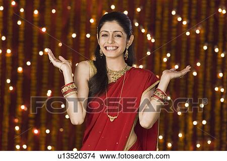 Picture - Woman shrugging in front of Diwali decoration. Fotosearch