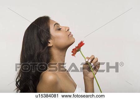 Stock Image - Woman smelling a daisy flower. Fotosearch