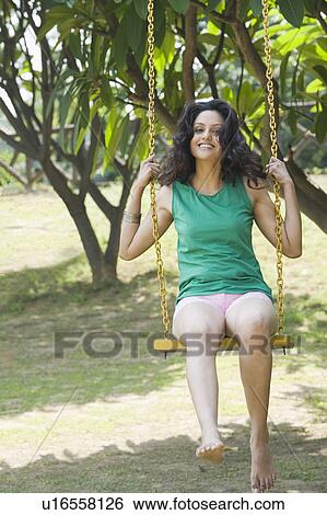 Woman smiling on a swing View Large Photo Image Stock Photograph - Woman smiling on a swing. Fotosearch