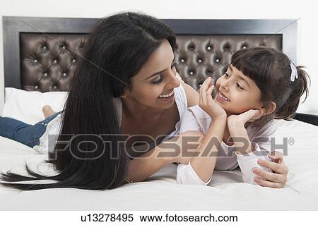 Woman smiling with her daughter on the bed View Large Photo Image Stock Photography - Woman smiling with her daughter on the bed. Fotosearch