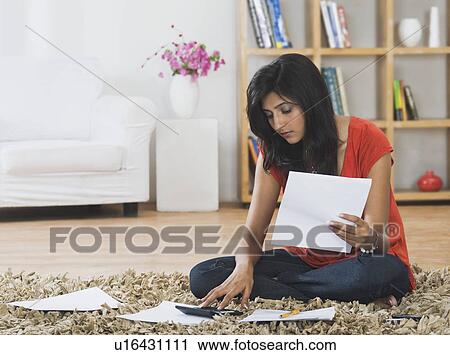 Stock Image - Woman sorting out bills at home. Fotosearch