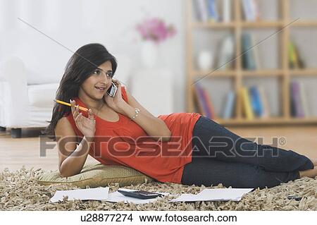 Woman sorting out bills while talking on a mobile phone View Large Photo Image Picture - Woman sorting out bills while talking on a mobile phone. Fotosearch
