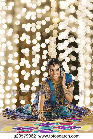 Woman talking on a mobile phone and making rangoli View Large Photo Image Stock Image - Woman talking on a mobile phone and making rangoli. Fotosearch