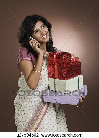 Woman talking on a mobile phone and holding gifts View Large Photo Image Stock Image - Woman talking on a mobile phone and holding gifts. Fotosearch
