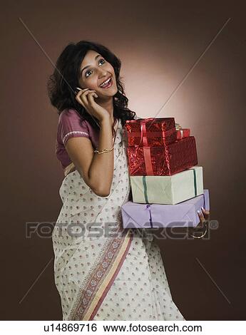 Woman talking on a mobile phone and holding gifts View Large Photo Image Stock Photograph - Woman talking on a mobile phone and holding gifts. Fotosearch