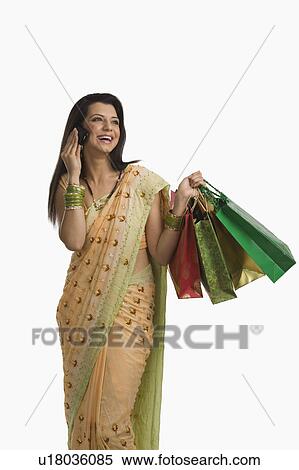 Woman talking on a mobile phone and holding shopping bags View Large Photo Image Stock Photography - Woman talking on a mobile phone and holding shopping bags. Fotosearch