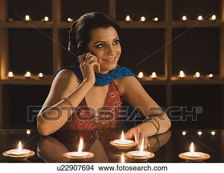 Picture - Woman talking on a mobile phone at Diwali festival. Fotosearch
