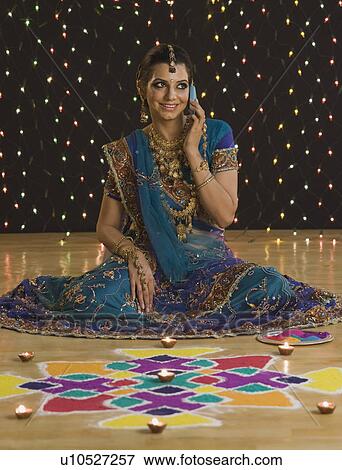 Stock Photo - Woman talking on a mobile phone near rangoli at Diwali festival. Fotosearch