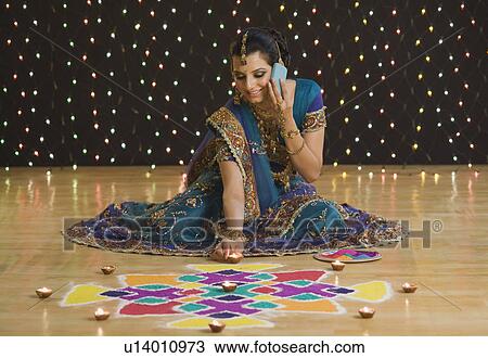 Woman talking on a mobile phone with decorating oil lamps near rangoli View Large Photo Image Stock Image - Woman talking on a mobile phone with decorating oil lamps near rangoli. Fotosearch