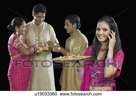 Stock Image - Woman talking on a mobile phone with her family in the background. Fotosearch
